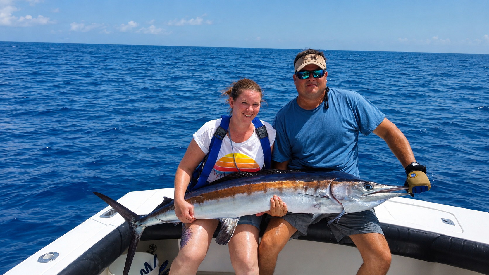 Captain Luis with a charter guest holding a large wahoo on the water