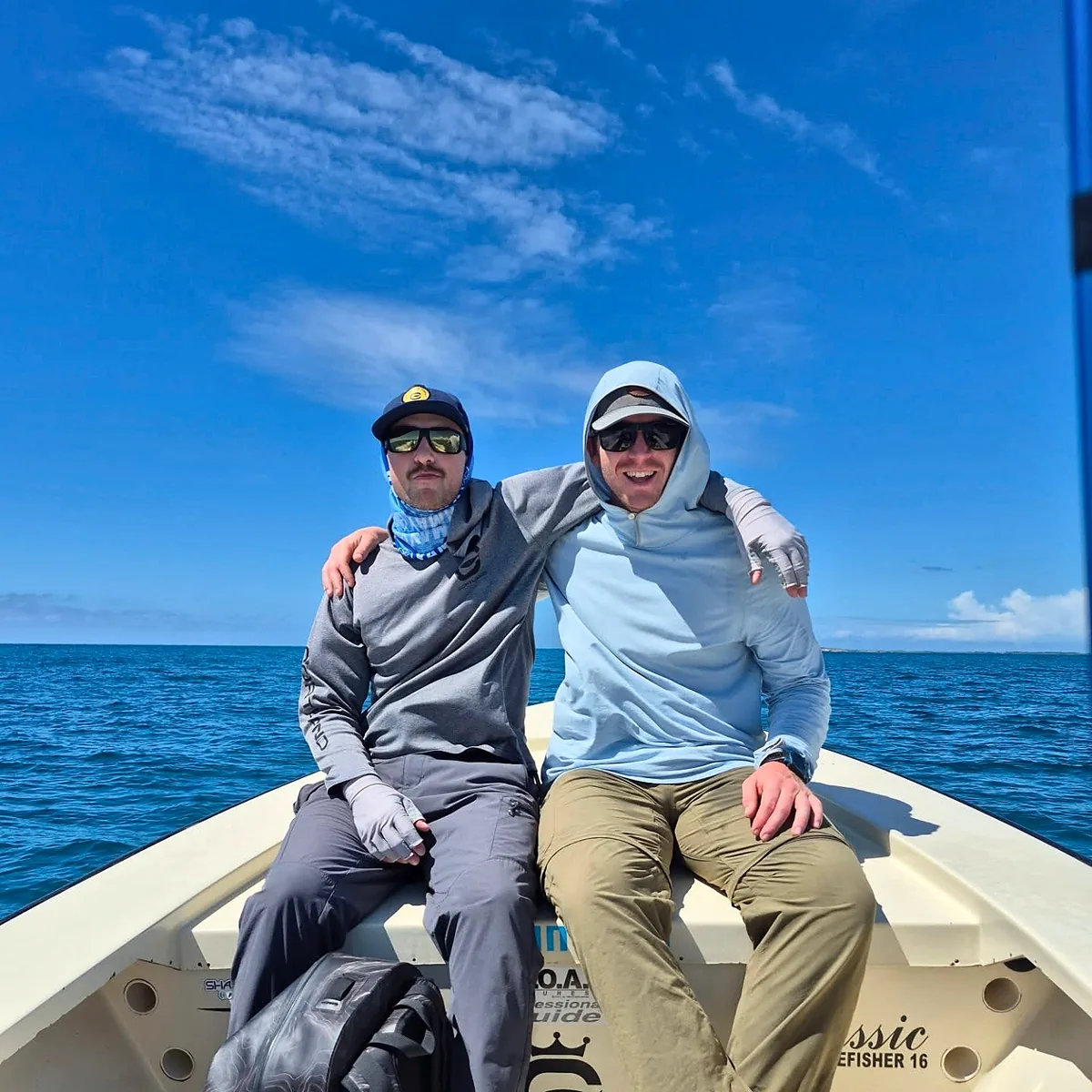 Two fishing guests seated together on a skiff in clear Puerto Rico waters.