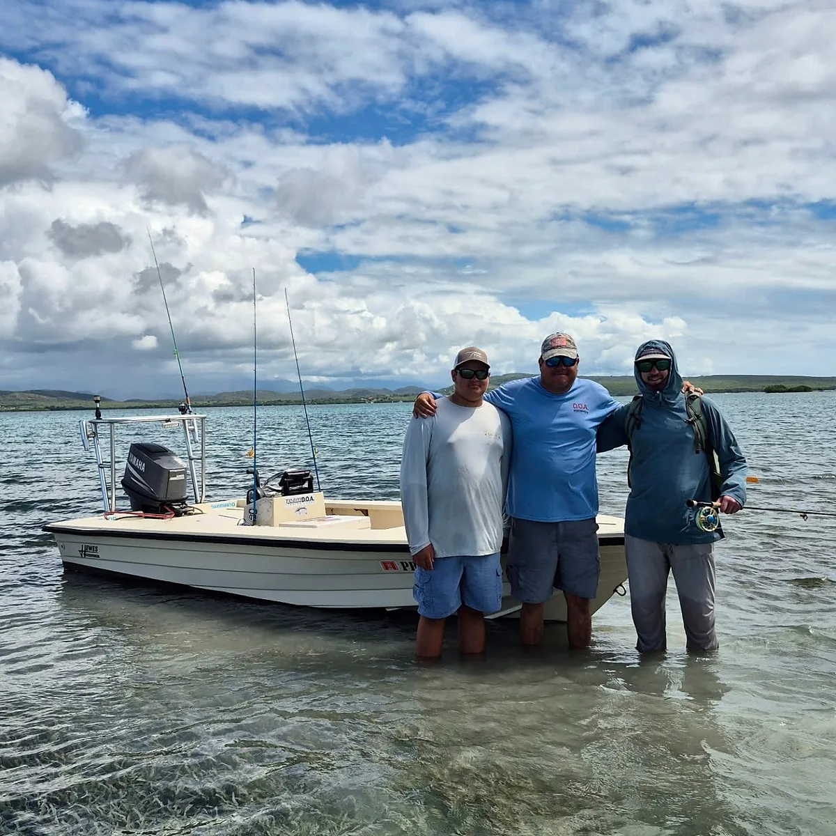 Fishing guests standing beside a shallow-water skiff in Puerto Rico.