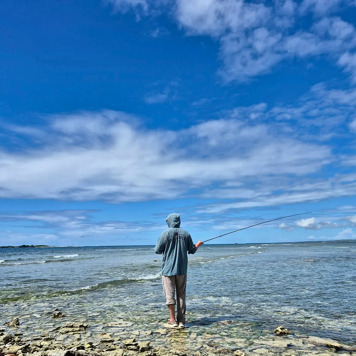 Angler wading and casting across shallow coastal flats in Puerto Rico.