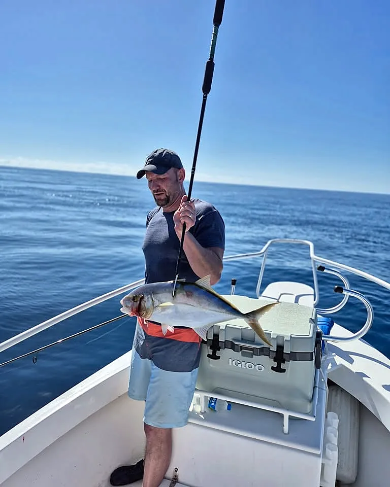 Guest holding an offshore catch on the bow of a Puerto Rico charter boat.