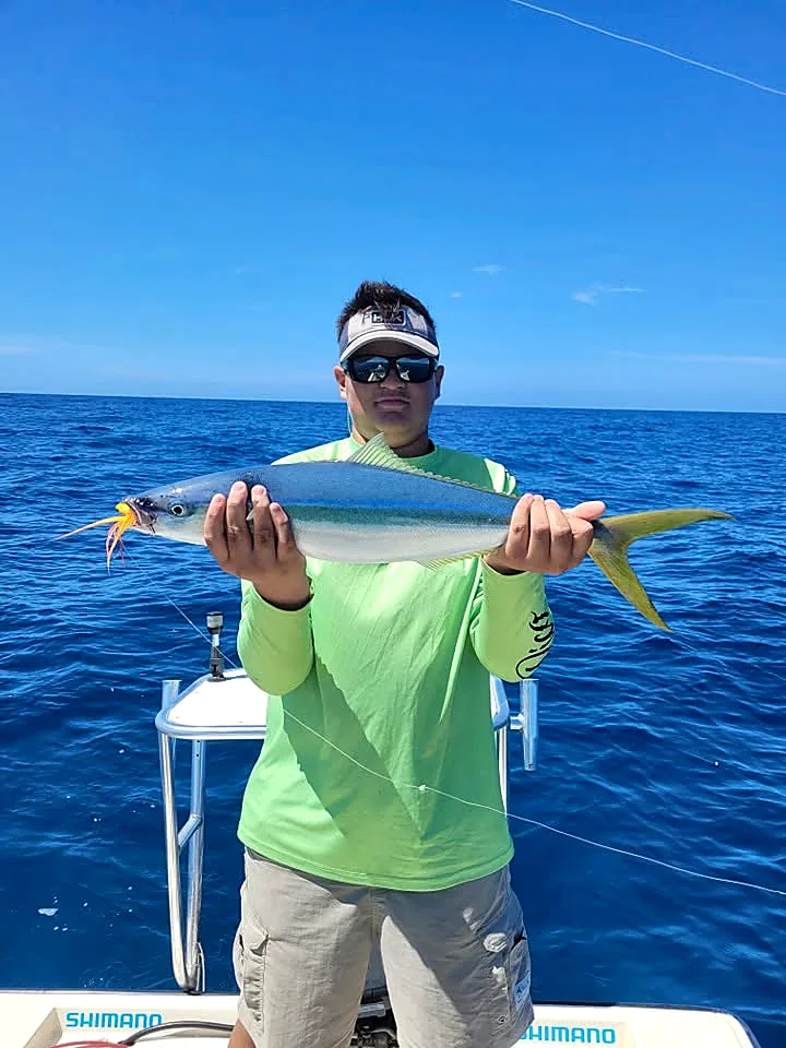 Angler holding an offshore catch over deep blue Puerto Rico water.