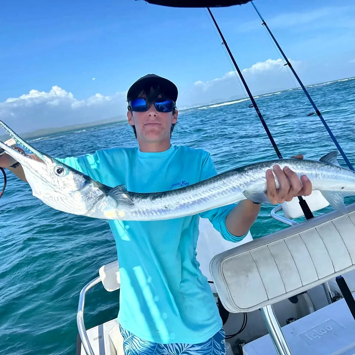 Young angler holding a barracuda aboard a Cabo Rojo fishing charter.