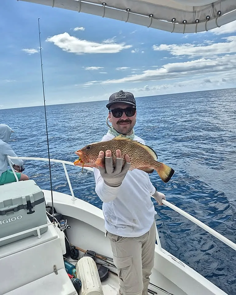 Smiling angler presenting a spotted reef fish in open water near Cabo Rojo.