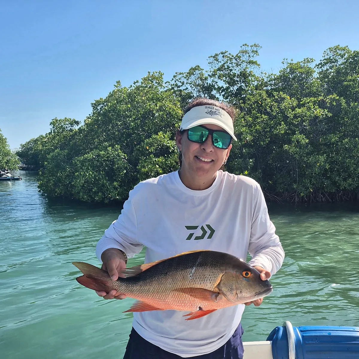 Guest smiling with a reef fish in shallow turquoise water in Puerto Rico.