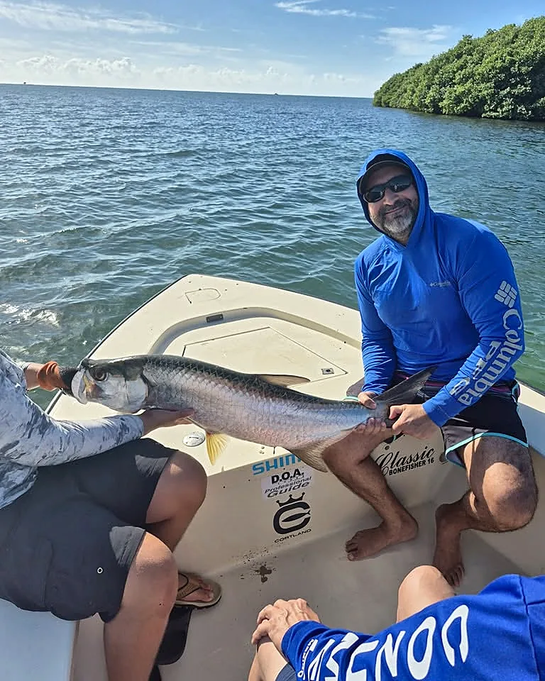 Angler kneeling with a large tarpon aboard a Cabo Rojo skiff.