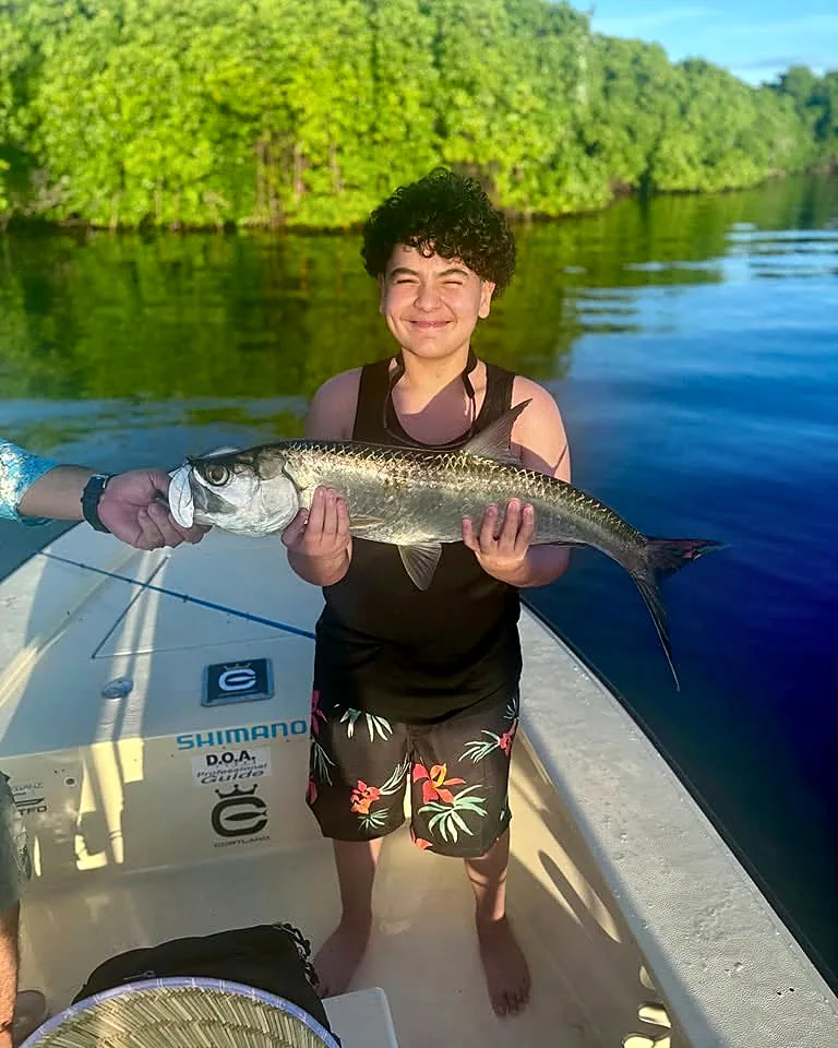 Young angler smiling while holding a tarpon near Puerto Rico mangroves.